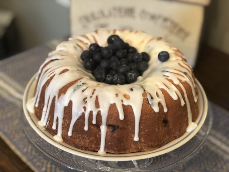 Pound cake on a plate with powdered sugar glaze icing and the middle filled with blueberries