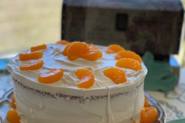 yellow layer cake with crunchy layer topping and creamy frosting. garnished with mandarin oranges.